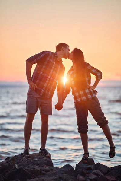 Et par elskende som kysser i vannet ved solnedgang. – stockfoto