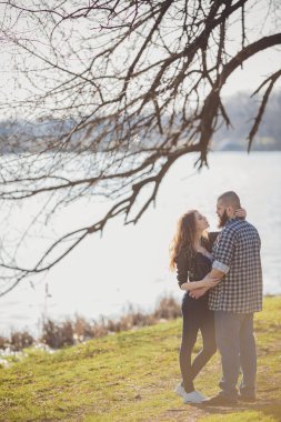 Parkta suyun yanında duran genç ve şık bir çift.