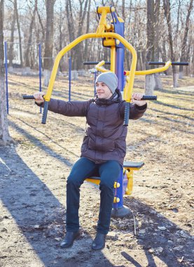 Adam parkta bir spor simülatörü yle meşgul.