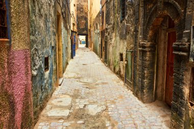 Eski şehrin dar sokağında yerleşim yerlerinin bej ve beyaz duvarları var. Essaouira, Fas.