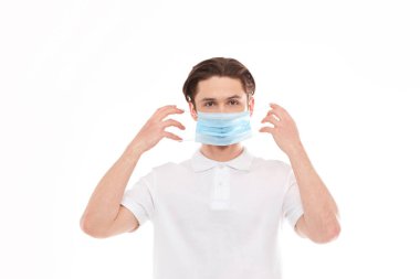 Avrupalı görünümlü beyaz tişörtlü bir adam tıbbi maske takıyor. Beyaz bir arkaplanda izole edilmiş