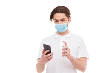 Maskeli bir Avrupalı telefonu dezenfekte ediyor. Covid-2019 salgınının konsepti.