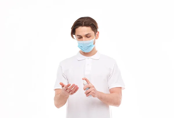 El hombre europeo con máscara se desinfecta las manos. Foto conceptual sobre el tema de la pandemia covid-2019 . — Foto de Stock