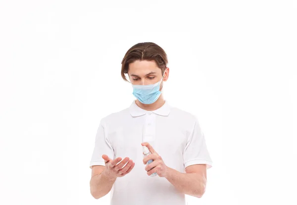 El hombre europeo con máscara se desinfecta las manos. Foto conceptual sobre el tema de la pandemia covid-2019 . — Foto de Stock