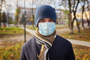 Elinde evrak çantası olan şapkalı genç bir adam tıbbi maskeyle işe gitmek için caddede yürüyor. Şehirde karantina, bir salgın var..