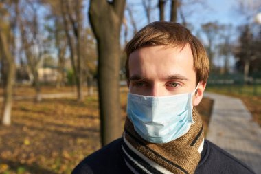Tek kullanımlık tıbbi maskeli bir gencin yakın plan portresi. Salgın. Coronavirus. Karantinaya alın. Maskeli genç adam. Covid 19. Tıp maskeli bir öğrenci..