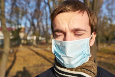 Tek kullanımlık tıbbi maskeli bir gencin yakın plan portresi. Salgın. Coronavirus. Karantinaya alın. Maskeli genç adam. Covid 19. Tıp maskeli bir öğrenci..