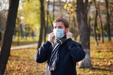Sokakta yüzüne tıbbi maske takan ceketli bir adam.