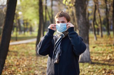 Sokakta yüzüne tıbbi maske takan ceketli bir adam.