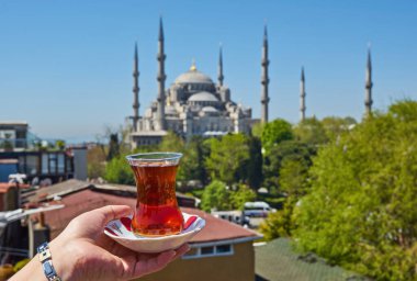 Türkiye 'nin İstanbul kentindeki Sultanahmet Camii olarak da bilinen Mavi Cami' nin önünde geleneksel Türk çayıyla el ele tutuşan bir kadın. İstanbul 'un başlıca eğlenceleri.