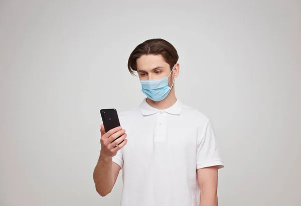 European man in a mask uses a telephone. Conceptual photo on the theme of the covid-2019 pandemic. Studio photo