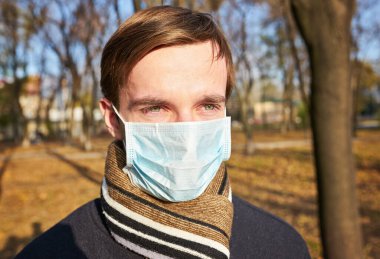 Tek kullanımlık tıbbi maskeli bir gencin yakın plan portresi. Salgın. Coronavirus. Karantinaya alın. Maskeli genç adam. Covid 19. Tıp maskeli bir öğrenci..