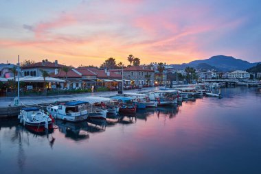 Marmaris marinası Türkiye 'nin Mugla kentinin güzel günbatımı şehir merkezi manzarası. Şehir ışıkları yat limanında, denizde, şehirde, dağlarda, yatlarda ve yelkenlilerde..