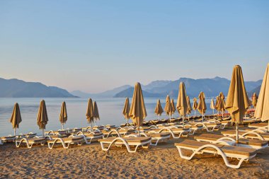 Sabahın köründe ıssız bir plaj. Şafakta kumsalda. Boş güneşlik. İnsansız plaj. Marmaris, Türkiye.