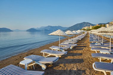 İnsansız kumsal ve güneş pansiyonları, şemsiyeler, palmiye ağaçları, Marmaris, Türkiye,