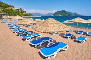 İnsansız kumsal ve güneş pansiyonları, şemsiyeler, palmiye ağaçları, Marmaris, Türkiye,