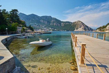 Türkiye 'nin Mugla, Turunc kentindeki tepenin tepesinde Ege Denizi' ndeki mavi lagün, arka planda plaj ve Türk bayrağı bulunan küçük tekneler.