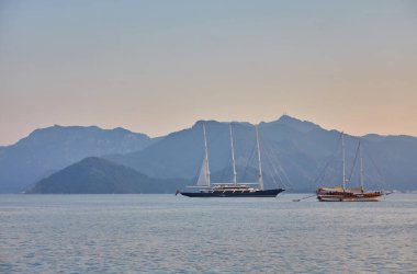 dağ ve yalnız motorlu tekne, sakin bir deniz olan Marmaris 'te gün doğumunu yansıttı, Türkiye