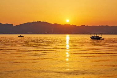 dağ ve yalnız motorlu tekne, sakin deniz Marmaris, Türkiye 'de günbatımını yansıttı