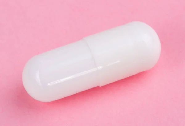 A rózsaszín háttér, fehér tabletta — Stock Fotó