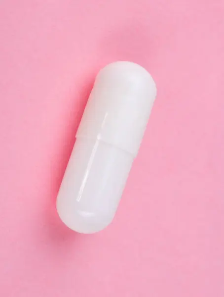 Pillola bianca su sfondo rosa — Foto Stock