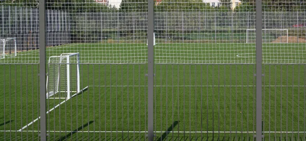 Güneşli bir günde çitin yanında futbol sahası — Stok fotoğraf