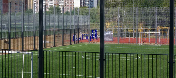 Campo de fútbol cerca de valla en el día día soleado —  Fotos de Stock