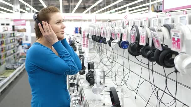 Happy Waman Está Probando Auriculares Tienda Moderna Uhd — Vídeos de Stock