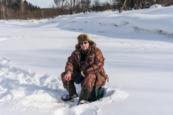 Il pescatore prende il pesce sul fiume nell'inverno — Foto Stock