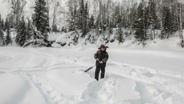El pescador en el río taladra hielo — Vídeos de Stock