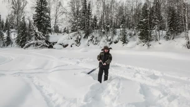 El pescador en el río taladra hielo — Vídeo de stock