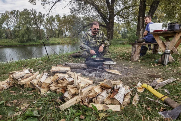 Dva muži vařit jídlo u táborového ohně — Stock fotografie