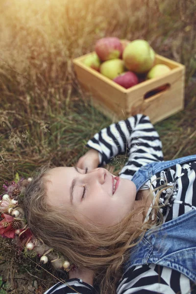 Relaxado e relaxado adolescente deitado na grama com maçãs — Fotografia de Stock