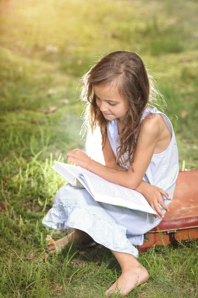 Lächelndes junges Mädchen beim Lesen eines Buches — Stockfoto