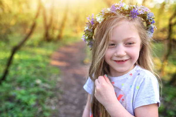 Mooi lachende jonge meisje in een krans van bloemen — Stockfoto