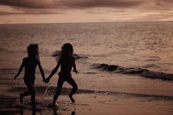 Dos chicas jóvenes corriendo en la playa — Foto de Stock