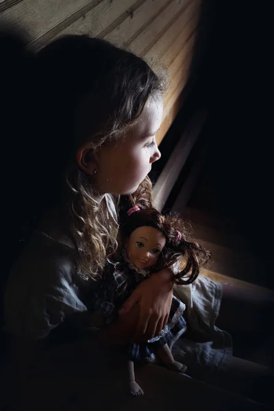 Lonely little girl cuddles a doll — Stock Photo, Image