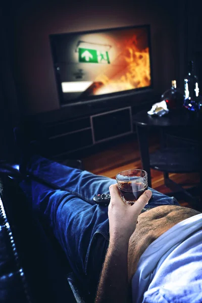 Mężczyzna leży na kanapie i pije alkohol — Zdjęcie stockowe