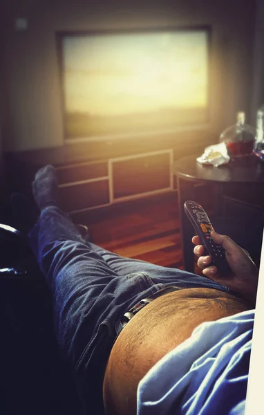 Chico en el sofá voltea canales en la televisión —  Fotos de Stock
