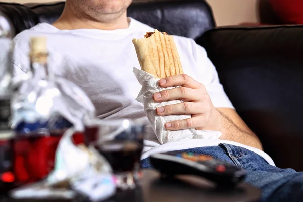 Τεμπέλης και λίπος άνθρωπος τρώει μια κεμπάπ στον καναπέ — Φωτογραφία Αρχείου