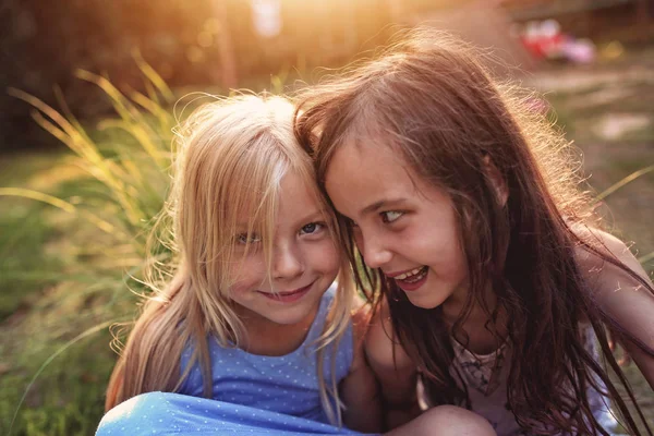 Dwie młode dziewczyny siedzą na zewnątrz — Zdjęcie stockowe
