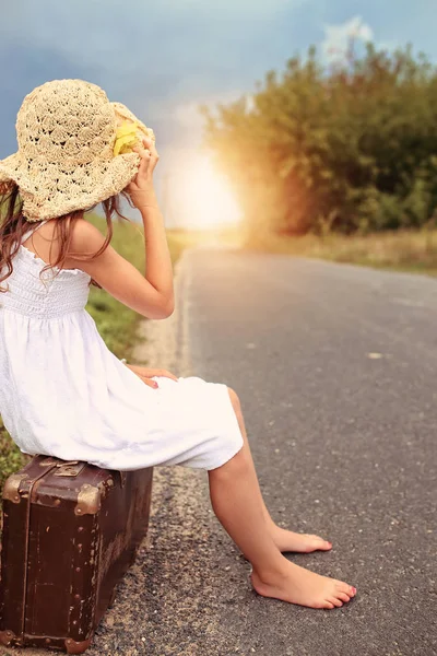 Küçük kız bir şapka bir bavul üzerinde oturan — Stok fotoğraf