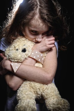 üzgün ve depresyonda kız bir oyuncak ayı tutuyor