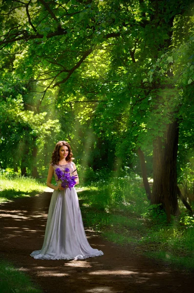 Frau mit Blumen im Wald (mit Sonnenstrahlen ver) — Stockfoto