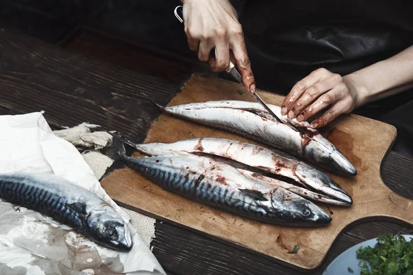 Женщина готовит рыбу-макрель — стоковое фото