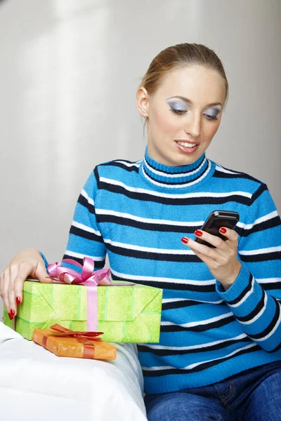 Mujer con caja de regalo usando smartphone —  Fotos de Stock