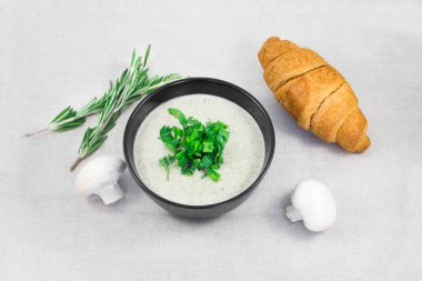 Mantar kremalı çorba, kruvasan, biberiye ve mantar ile masaya greenary. Öğle yemeği için lezzetli taze çorba.