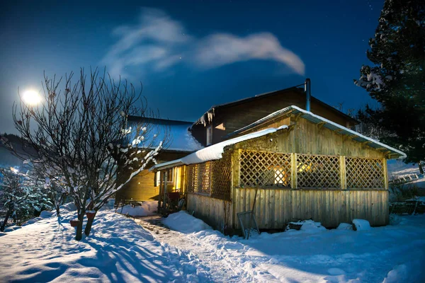 Maison en bois dans la neige la nuit d'hiver — Photo
