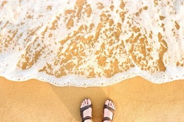 Kadının ayak plaj kum üzerinde Sandaletler içinde