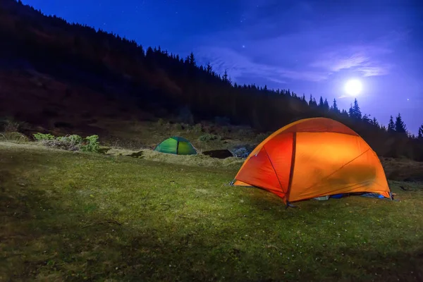 Illuminated orange and green camping tents — Stock Photo, Image